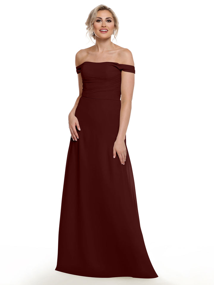 A woman in Avery Austin’s 80136, an off-the-shoulder dark red chiffon gown with a floor-length silhouette, stands against a white background, smiling softly with her hands relaxed by her sides.