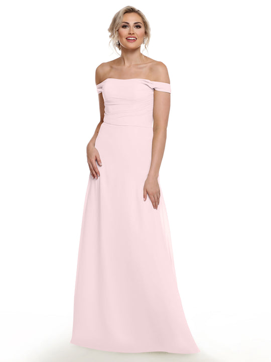 A woman models the Avery Austin TH-80136: a light pink, off-the-shoulder chiffon gown. She stands against a white background, her blonde hair styled up, smiling gently with one hand at her side in the elegant floor-length dress.