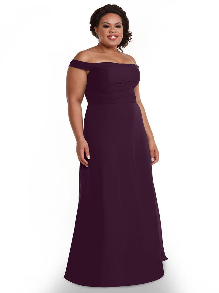 A woman stands smiling against a plain white background, wearing the Avery Austin 80136 off-the-shoulder, floor-length chiffon dress in deep purple.