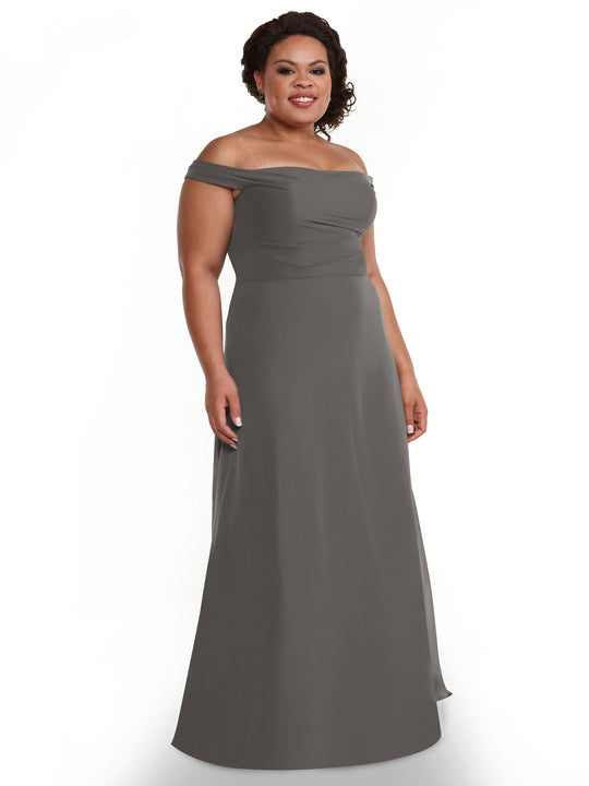 A woman models the Avery Austin TH-80136, an off-the-shoulder, floor-length chiffon dress, standing against a plain white background and smiling with her hands relaxed at her sides.