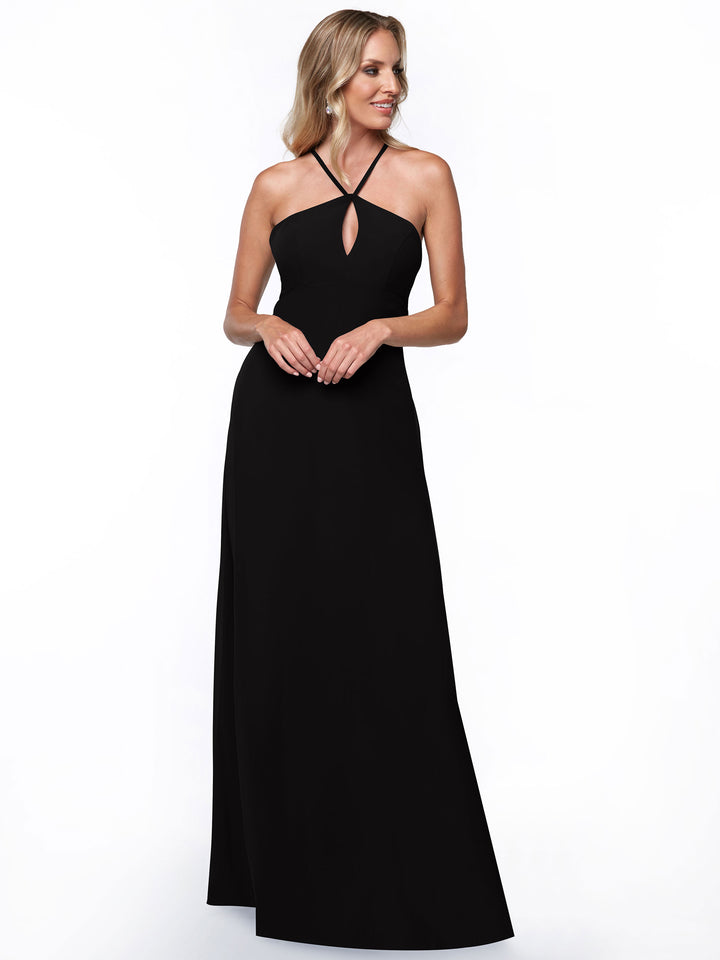 A woman stands and smiles with her hands clasped, wearing Avery Austin&