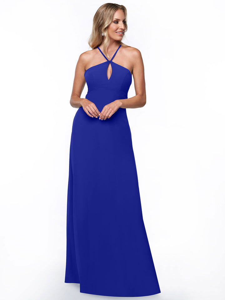 A woman models the Avery Austin 80137, a minimalistic floor-length royal blue halter dress with a keyhole neckline and crossed straps, against a plain white background.