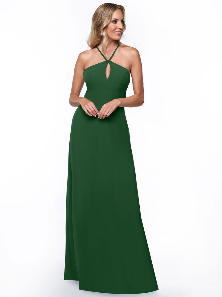A woman wears Avery Austin style 80137, a sleeveless, floor-length dark green halter dress with keyhole cutout and subtle keyhole back, standing against a white background with her hands clasped and smiling slightly.