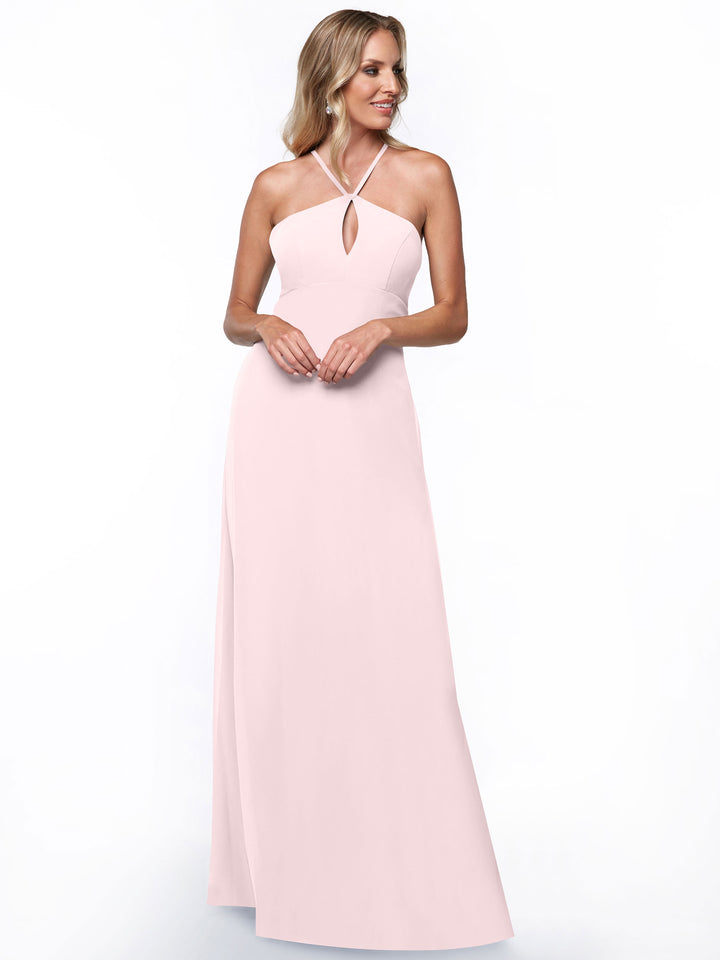 Model wears Avery Austin style 80137, a long pale pink halter dress featuring keyhole cutouts at the chest and back, as she stands against a plain white background with a slight smile.