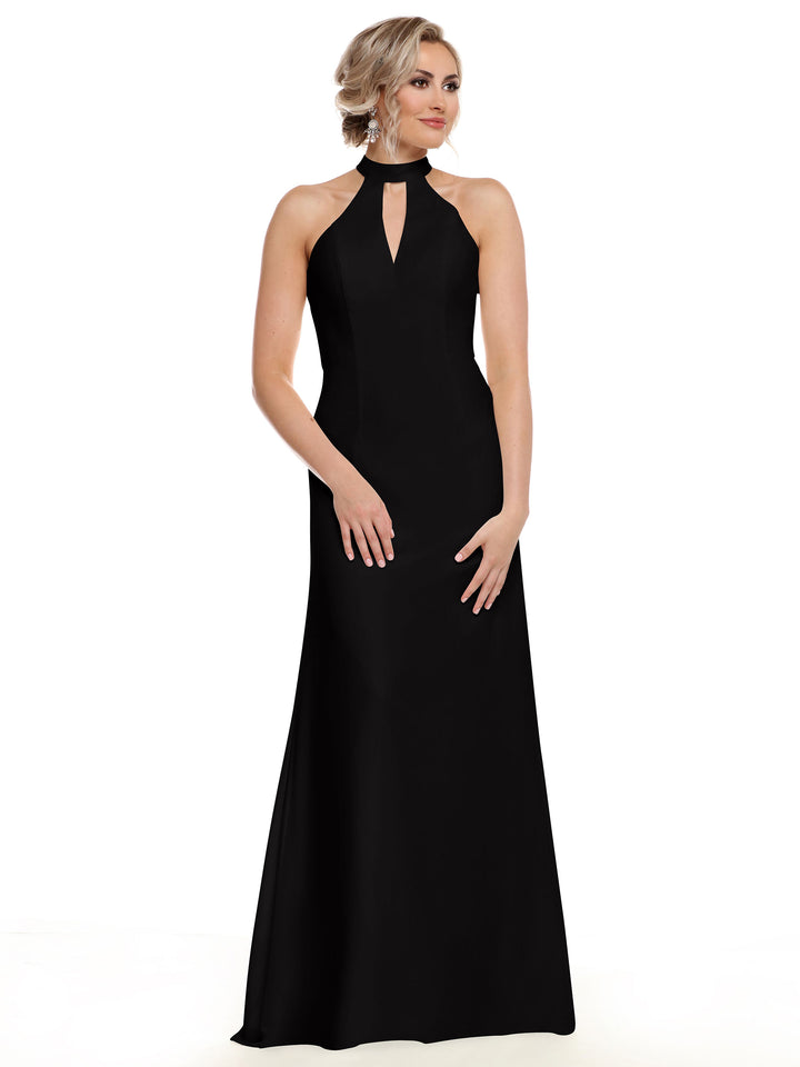 A woman models Avery Austin style 80138, a sleeveless, floor-length black gown with an open back and halter neckline. She stands against a white background with her light hair in an updo, gazing slightly left.