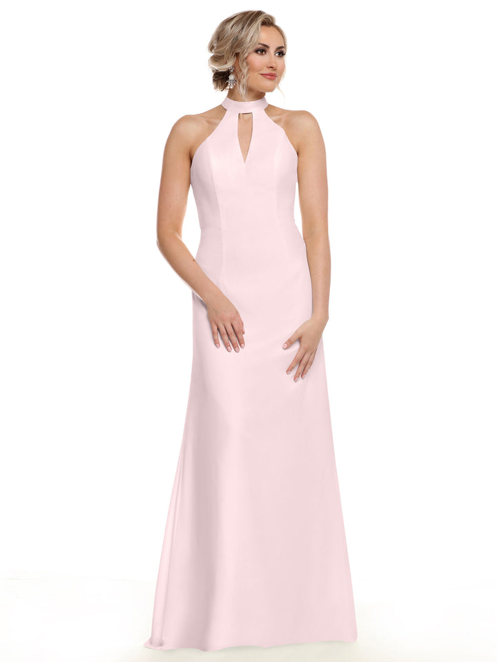 A woman models Avery Austin’s 80138, a sleeveless pale pink gown with a halter neckline and front keyhole cutout, standing against a white background to showcase effortless elegance.