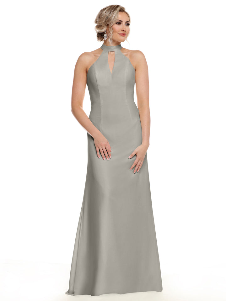 A woman poses in Avery Austin’s 80138—a long, sleeveless light gray gown with a halter neckline and keyhole cutout—against a white background. Her hair falls in loose waves.