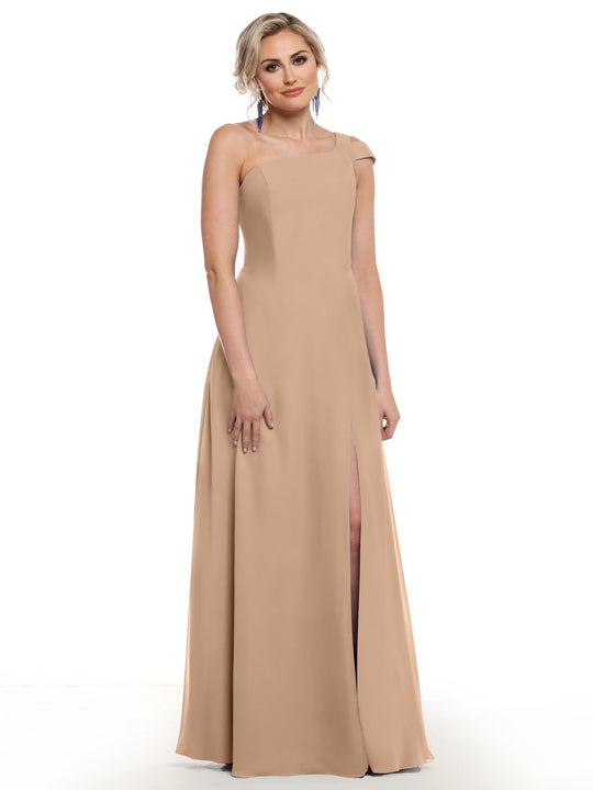 A woman models Avery Austin’s floor-length buff side slit dress (style 80139) against a white background, looking at the camera with a gentle smile.