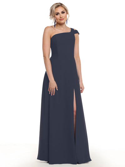 A woman stands against a white background, posing in Avery Austin style 80139—a floor-length navy blue one-shoulder dress with a thigh-high side slit. Her light hair is styled up and her arms are relaxed by her sides.