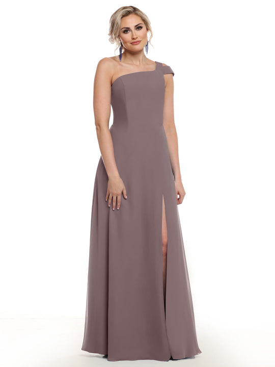 A woman models Avery Austin’s mauve one-shoulder dress (Style 80139) featuring a thigh-high side slit. She stands against a white background, her blonde hair styled up, smiling softly at the camera.
