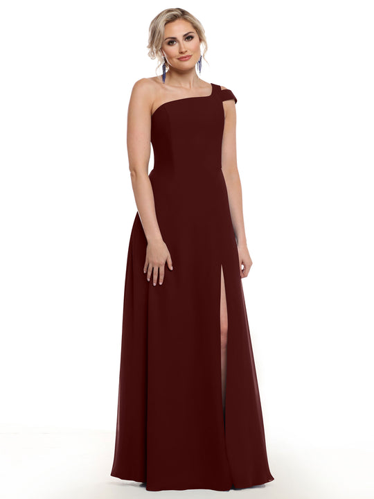 A woman models Avery Austin’s 80139, a chic floor-length merlot one-shoulder gown with a thigh-high slit, posed against a white backdrop.