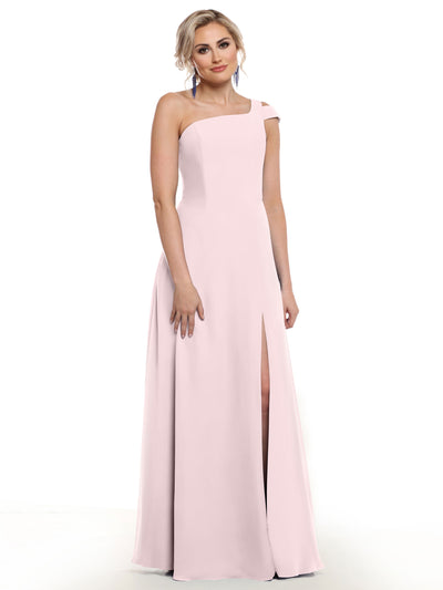 A woman models Avery Austin’s 80139: a light pink, floor-length dress with an asymmetrical one-shoulder neckline and thigh-high side slit, standing against a plain white background.