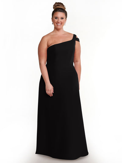A woman with light skin and brown hair in a bun is wearing the Avery Austin 80139 long black one-shoulder dress with a side slit and drop earrings, smiling against a plain white background.