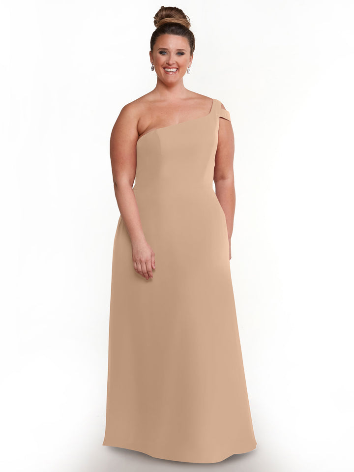 A woman wears the Avery Austin 80139 dress in buff, styled with a neat bun and earrings, standing and smiling against a plain white background.