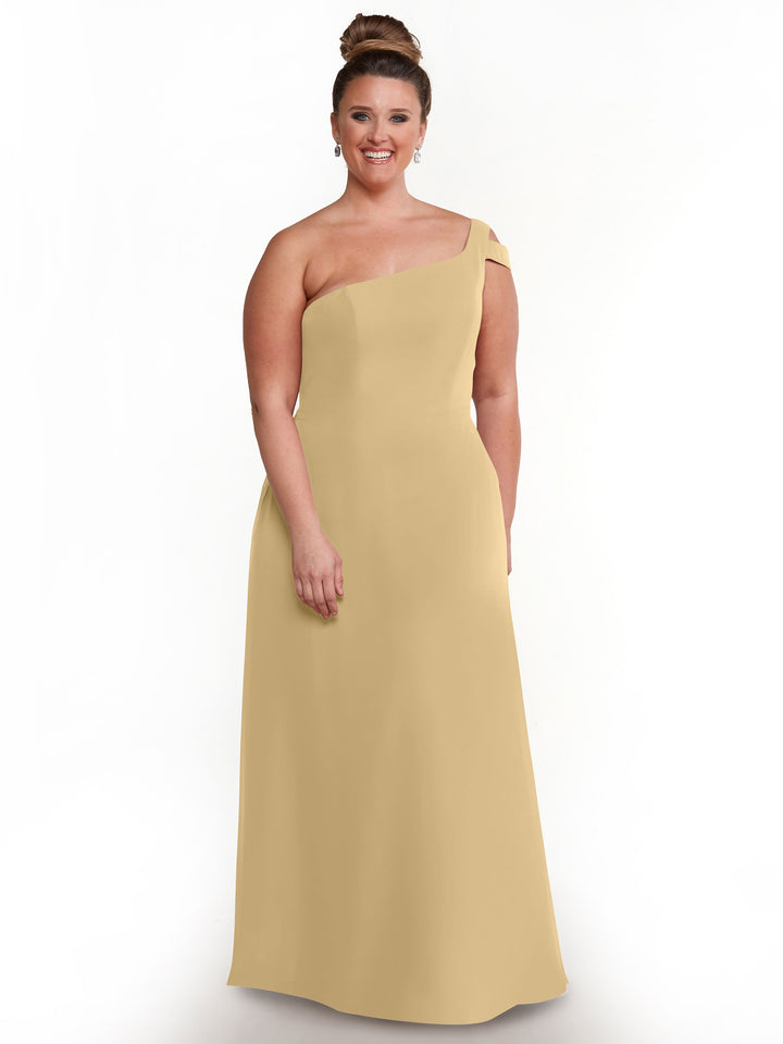 A woman smiles in the Avery Austin 80139, a champagne one-shoulder gown, against a plain white background. Her hair is styled in a high bun and she wears drop earrings.