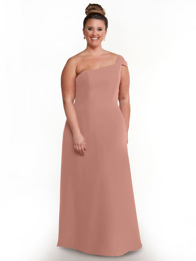 A woman smiles against a white background, wearing the Avery Austin 80139 mauve one-shoulder long dress. Her hair is in a neat bun, complemented by drop earrings.