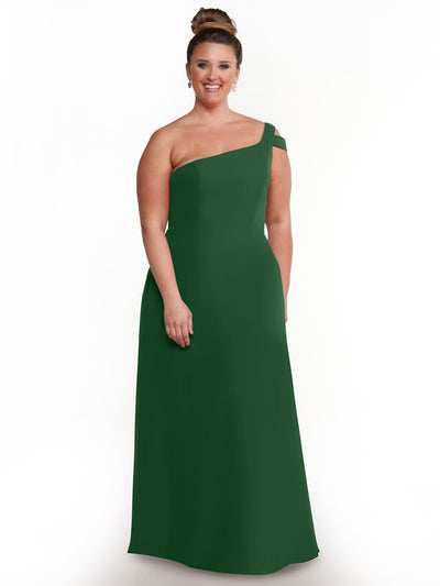 A woman in the Avery Austin 80139, a floor-length one-shoulder dark green dress, stands smiling against a white background with her hair in a bun and earrings.