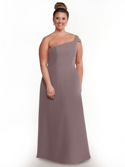 A woman models Avery Austin’s 80139, a mauve one-shoulder dress, standing against a white background with her hair in a high bun and wearing elegant drop earrings.