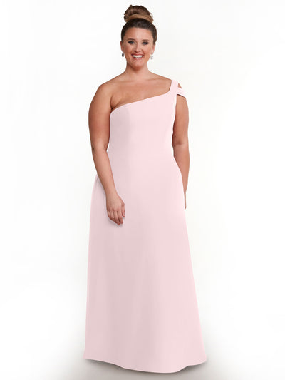 A smiling woman with light brown hair in a bun models Avery Austin’s 80139, a pale pink, one-shoulder, floor-length dress, standing against a plain white background.