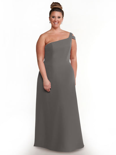 A woman smiles against a white background, wearing Avery Austin’s 80139—a long, sophisticated one-shoulder gray dress—with her hair styled in an elegant bun.