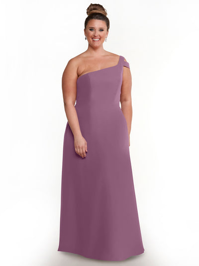 A woman smiles in the Avery Austin 80139, a mauve one-shoulder floor-length dress, with her hair in a high bun, highlighting its elegant silhouette against a plain white background.