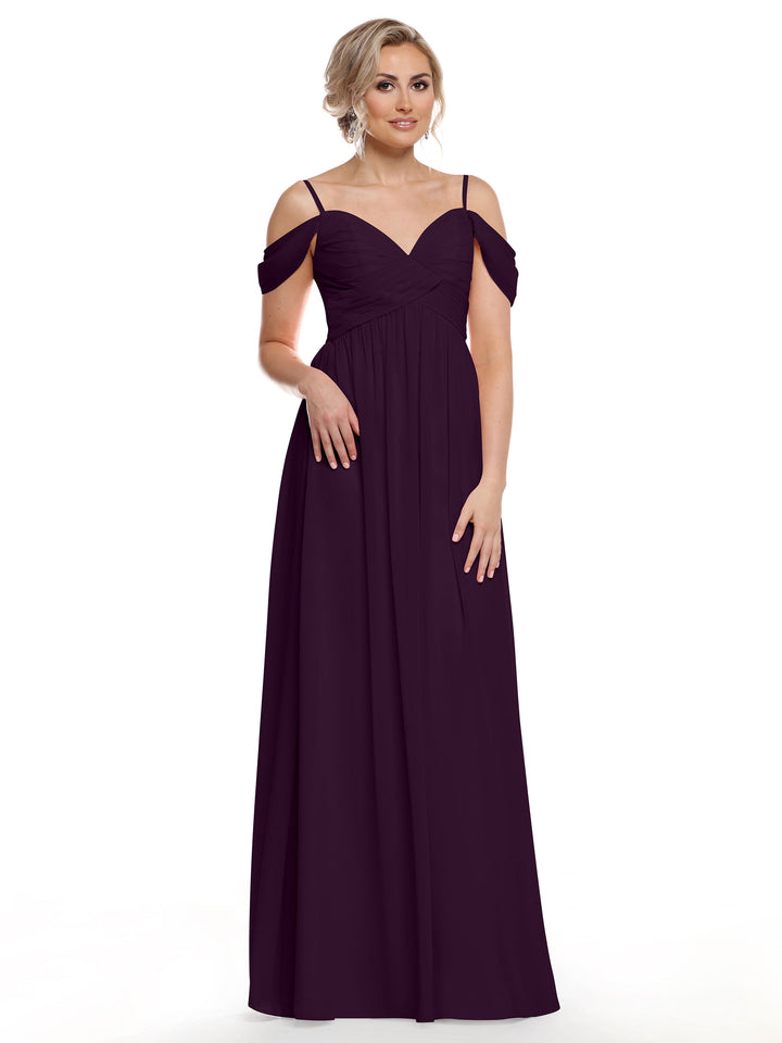 A woman models the Avery Austin 80142, a boho chic, floor-length dark purple cold shoulder dress with spaghetti straps, against a plain white background.