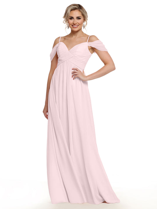 A woman wearing the Avery Austin TH-80142 long light pink chiffon cold shoulder dress with draped sleeves stands smiling against a plain white background.