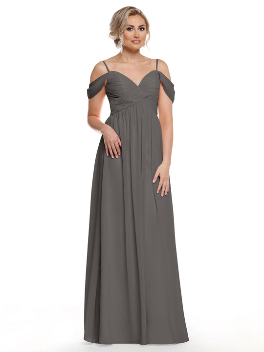 A woman wearing Avery Austin’s 80142 dress in steel gray chiffon with thin straps and a sweetheart neckline stands against a white background, her light hair styled up and accessorized with earrings.