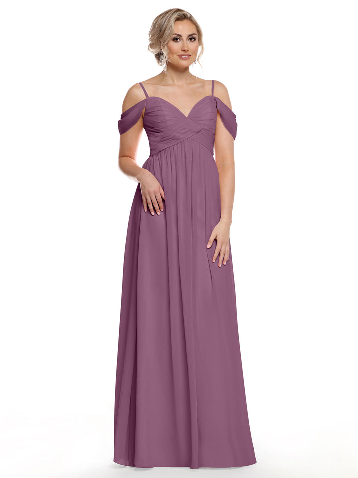A woman models Avery Austin’s 80142: a mauve, floor-length chiffon dress with spaghetti straps, sweetheart neckline, and ruched bodice, standing against a plain white background.