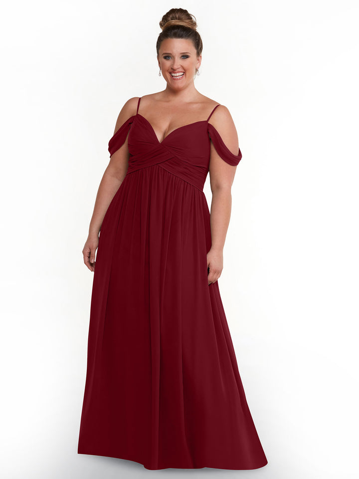 A smiling woman with a high bun models the Avery Austin TH-80142, a floor-length, off-the-shoulder deep red chiffon dress with spaghetti straps, standing against a plain white background.