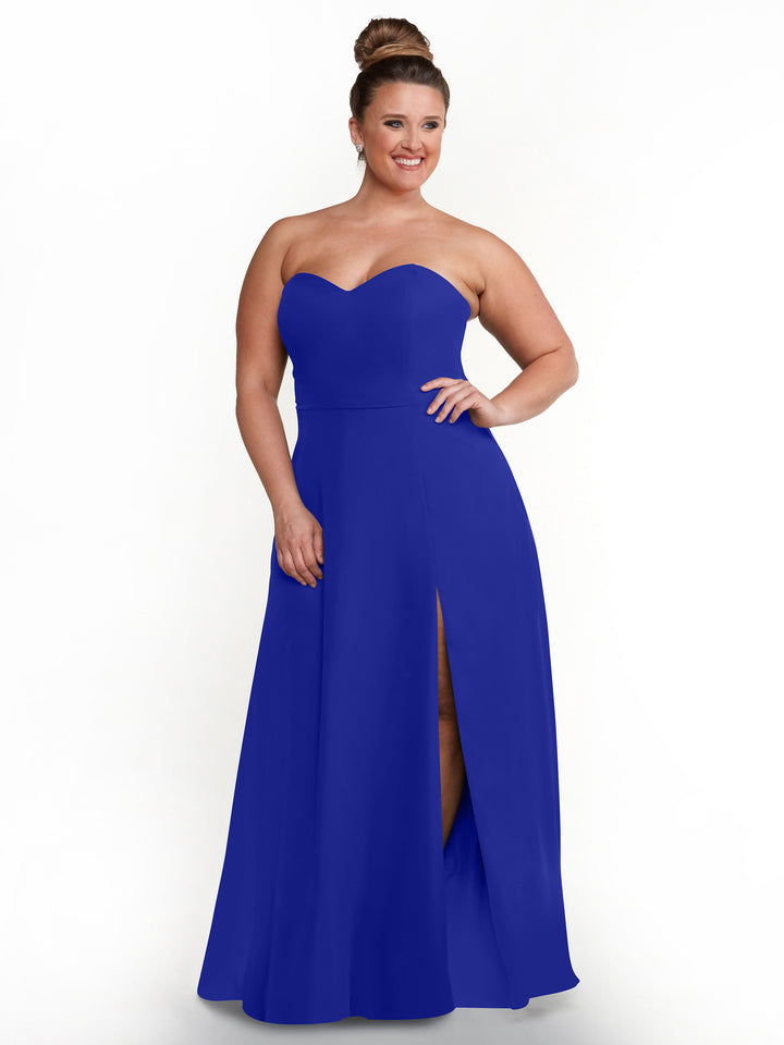 A woman models the Avery Austin 80143 dress—a royal blue, strapless sweetheart gown with a floor-length skirt and side slit—posing and smiling against a plain white background.