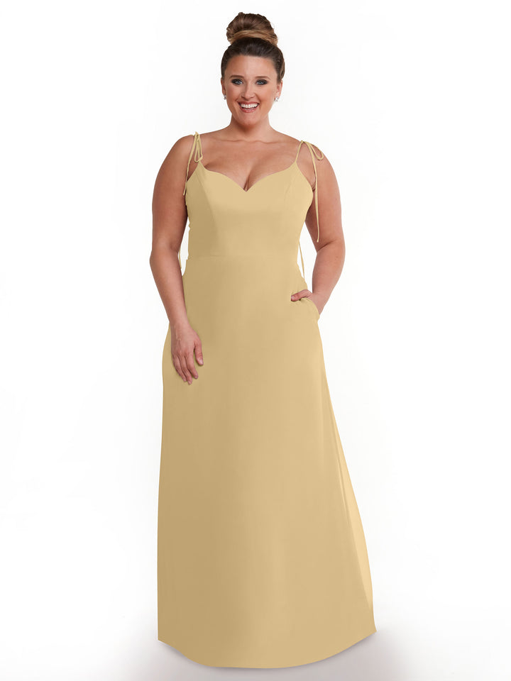 A woman with her hair in a bun wears the Avery Austin 80144 sleeveless, light yellow chiffon dress with thin straps. She smiles while standing against a plain white background.
