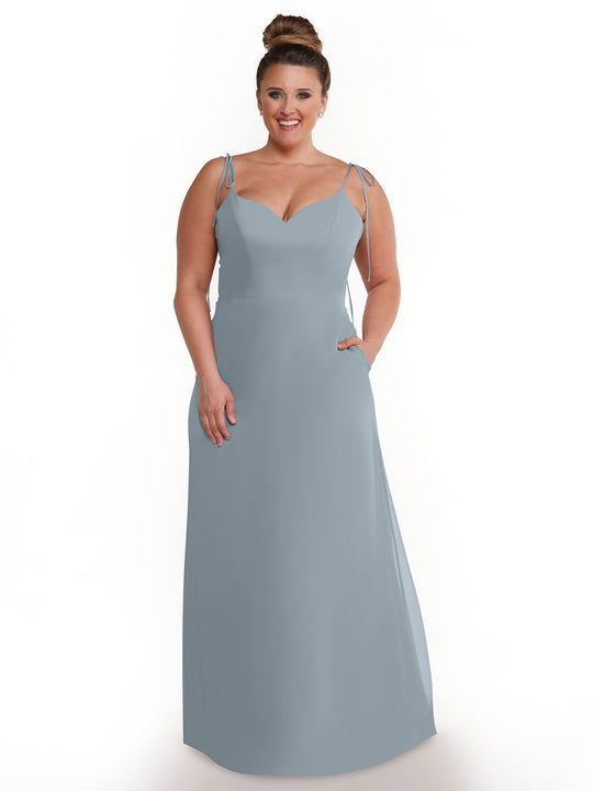 A woman with brown hair in a high bun models the Avery Austin 80144—a long light blue chiffon dress with thin straps and a sweetheart neckline—standing against a plain white background.