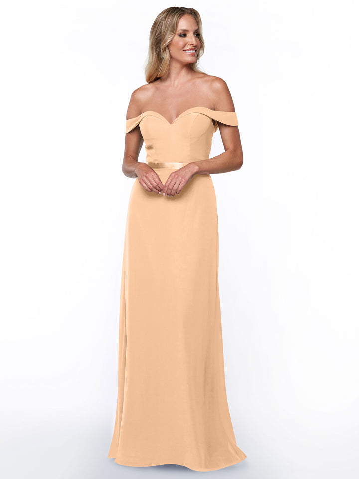 A woman smiles and stands with hands gently clasped in front, modeling Avery Austin&