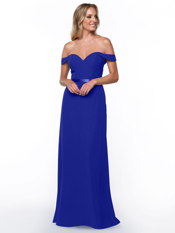 A woman smiles against a plain white background wearing Avery Austin style 80145—a royal blue, off-the-shoulder bridesmaid dress with a fitted bodice and relaxed skirt.