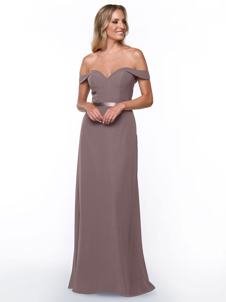 A woman wears Avery Austin’s 80145, a mauve off-the-shoulder bridesmaid dress with a sweetheart neckline, fitted bodice, and floor-length A-line silhouette. She stands smiling slightly against a plain white background.