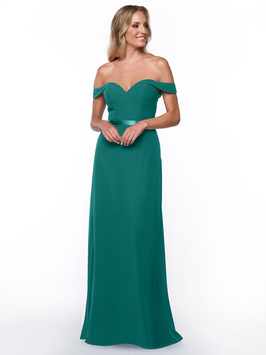 A woman wears the Avery Austin 80145 floor-length, off-the-shoulder bridesmaid dress with a fitted bodice and sweetheart neckline, standing against a white background, smiling and looking to the side.