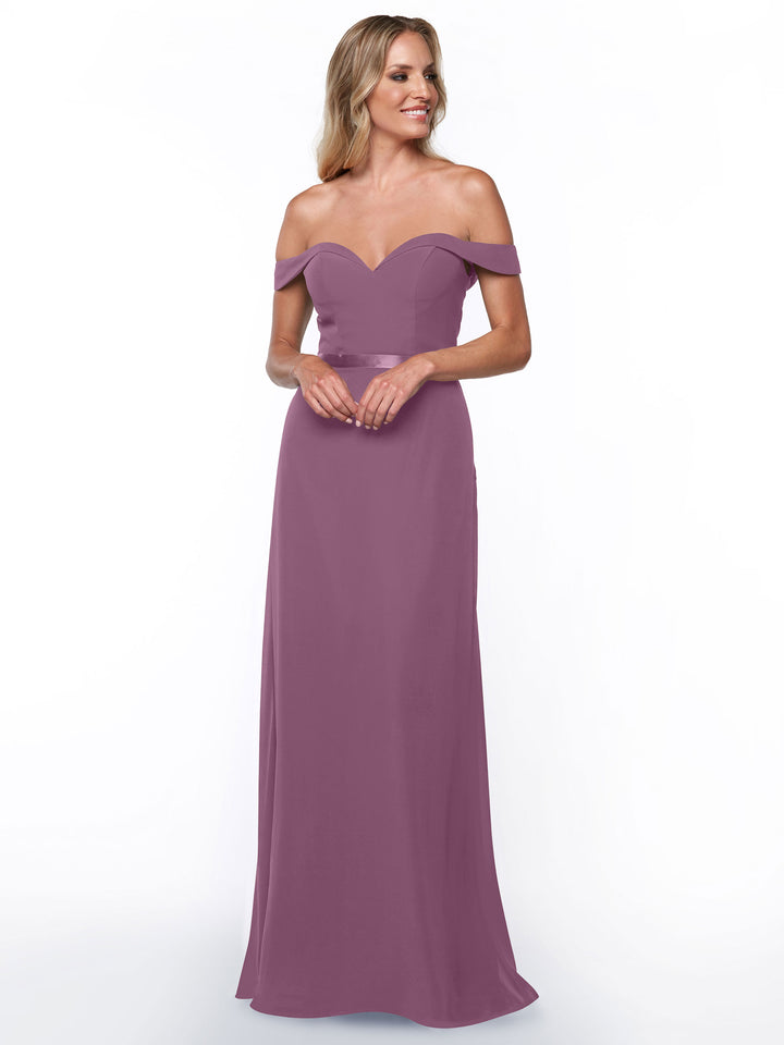 A woman smiles against a white background, wearing Avery Austin style 80145—a mauve, off-the-shoulder bridesmaid dress with a sweetheart neckline and flowing floor-length chiffon skirt.