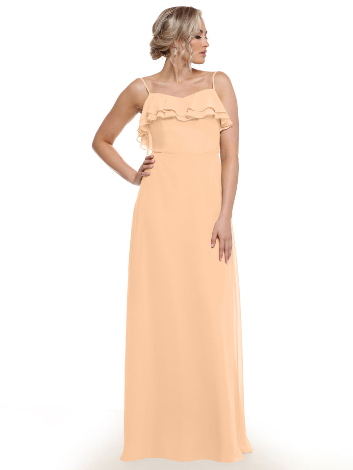 A woman models Avery Austin’s 80146: a sleeveless, floor-length peach chiffon A-line dress with tiered chest ruffles. She stands against a white background, looking to the side.