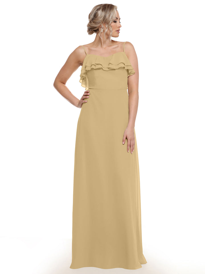 A woman stands slightly to the side, one hand on her hip, wearing Avery Austin’s 80146—a long, light yellow chiffon A-line dress with tiered chest ruffles—against a plain white background.