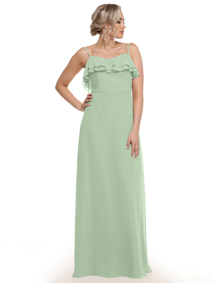 A woman with blonde hair in an updo stands against a white background, wearing the Avery Austin TH-80146: a light green chiffon A-line dress featuring thin straps and tiered ruffles across the bust. She gazes to the side.
