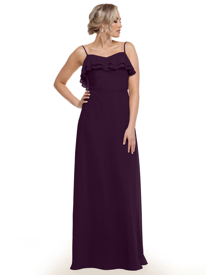 A woman models Avery Austin style 80146, a sleeveless, floor-length dark purple chiffon A-line dress with thin straps and tiered chest ruffles, standing with one hand on her hip against a plain white background.