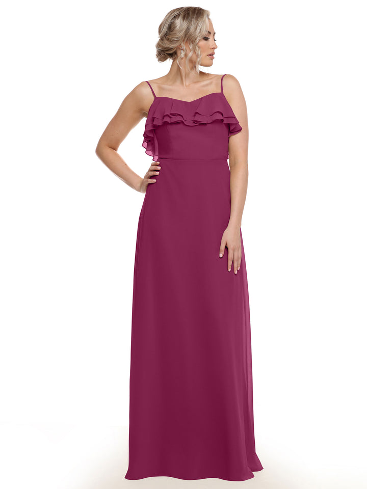 A woman models Avery Austin’s 80146 sleeveless magenta chiffon A-Line dress with ruffled bodice, standing against a plain white background, looking left with one hand on her hip.