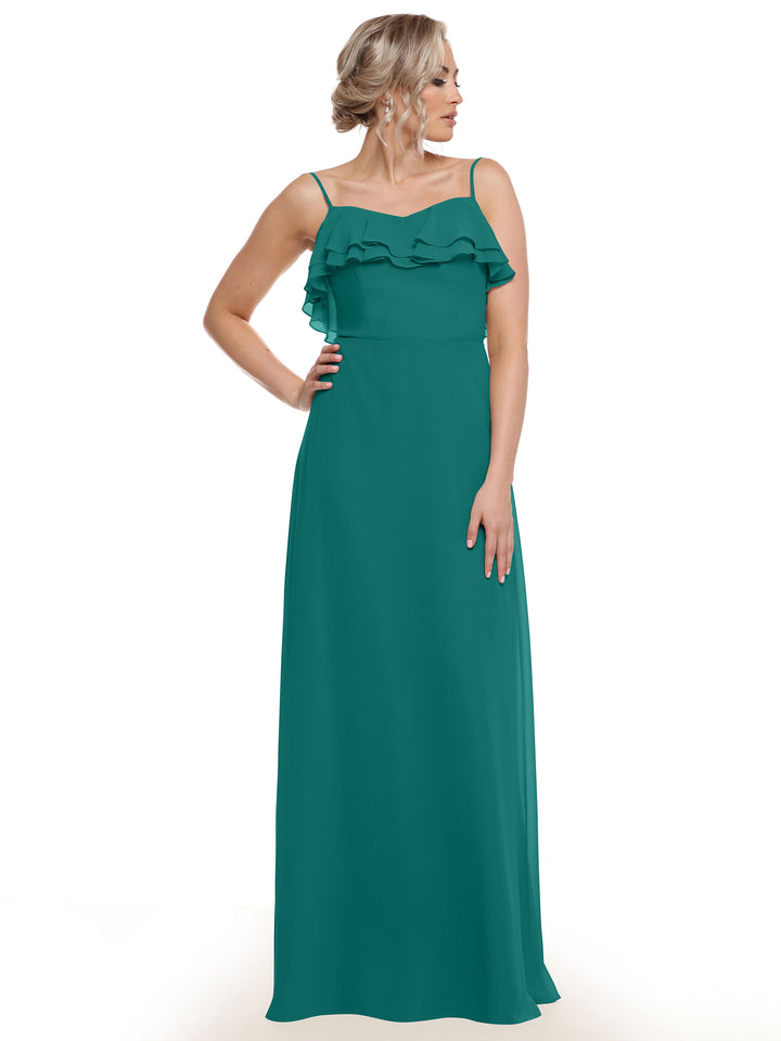 A woman models Avery Austin’s 80146 sleeveless teal chiffon A-line dress, featuring thin straps and tiered bust ruffles, posing with one hand on her hip against a white background.
