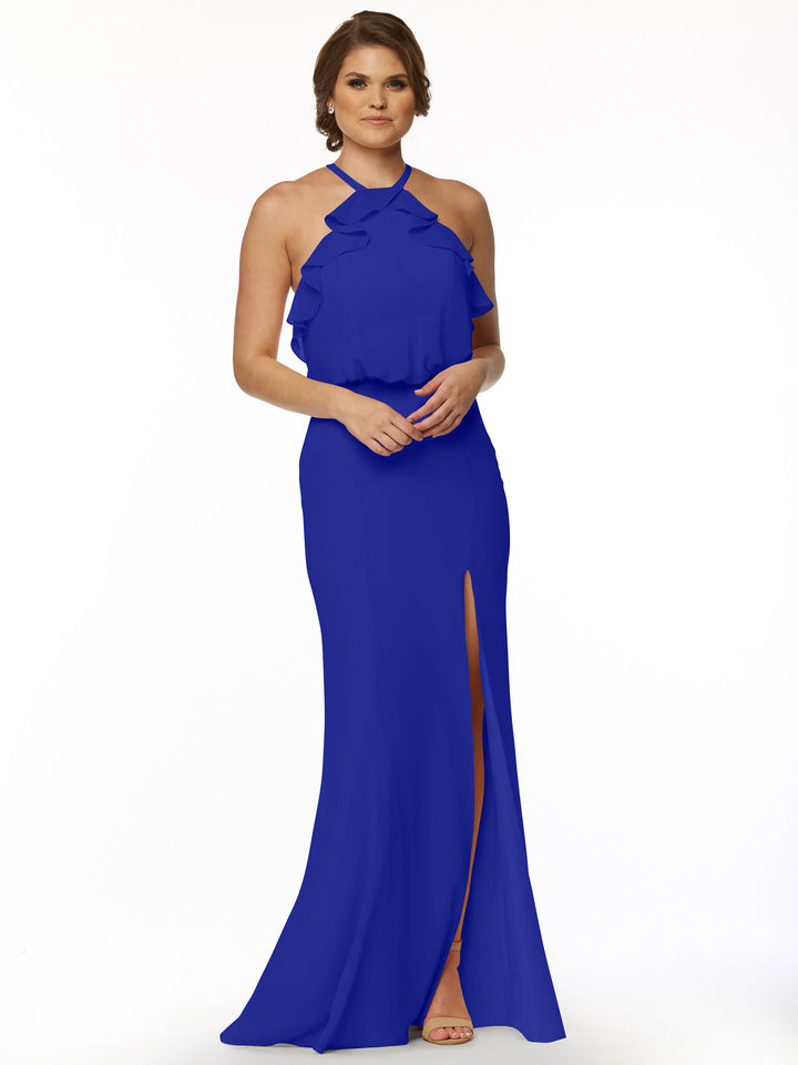 A woman with short brown hair and open-toe heels models Avery Austin’s 80147: a fitted chiffon dress featuring a ruffled halter top and thigh-high side slit, posed against a plain white background.