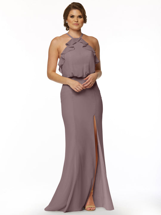 A woman poses against a white background wearing Avery Austin's 80147—a mauve, floor-length chiffon dress with a ruffled halter top and front slit. She has short hair and pairs the look with open-toed heels.