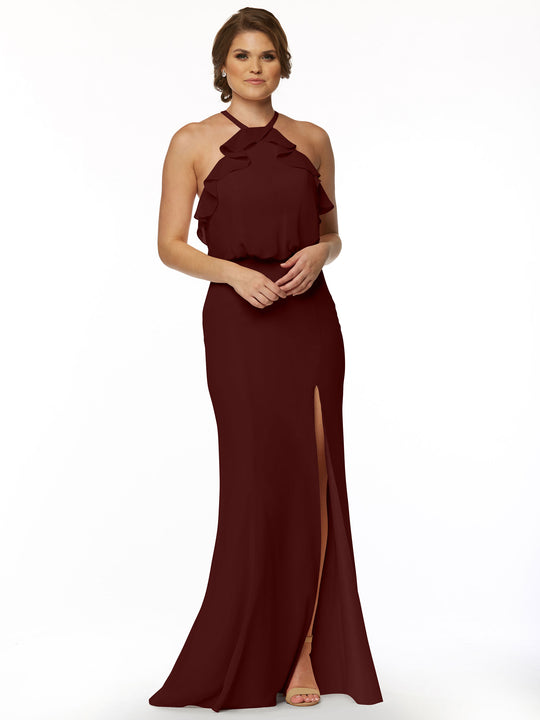 A woman models Avery Austin’s 80147, a sleeveless floor-length burgundy chiffon dress with a ruffled halter top and front leg slit, standing against a plain white background.