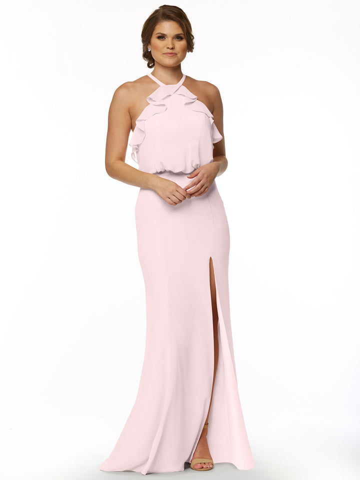 A woman models Avery Austin’s 80147: a sleeveless, light pink fitted chiffon dress with a ruffled halter top and front slit, standing against a plain white background with her hands clasped in front.