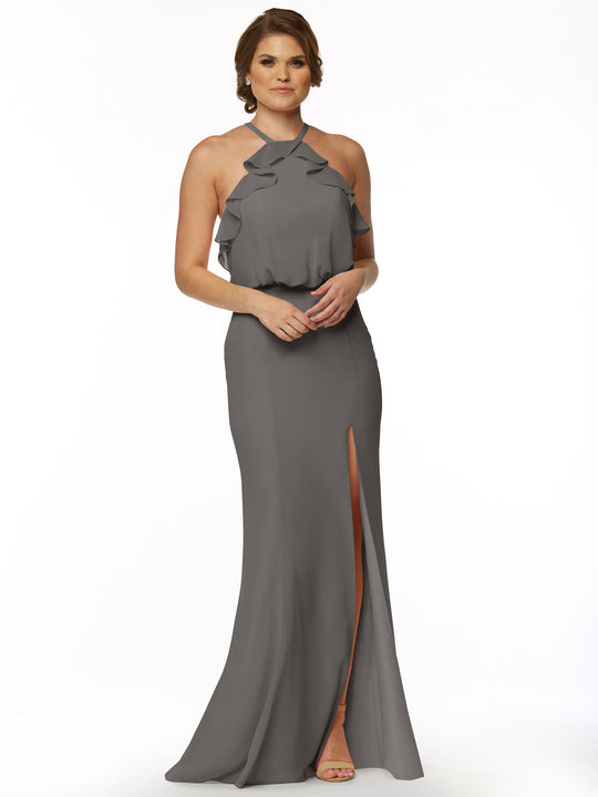 A woman stands on a white background wearing Avery Austin’s 80147 sleeveless, floor-length chiffon dress featuring a fitted silhouette, ruffled halter top, and front slit.