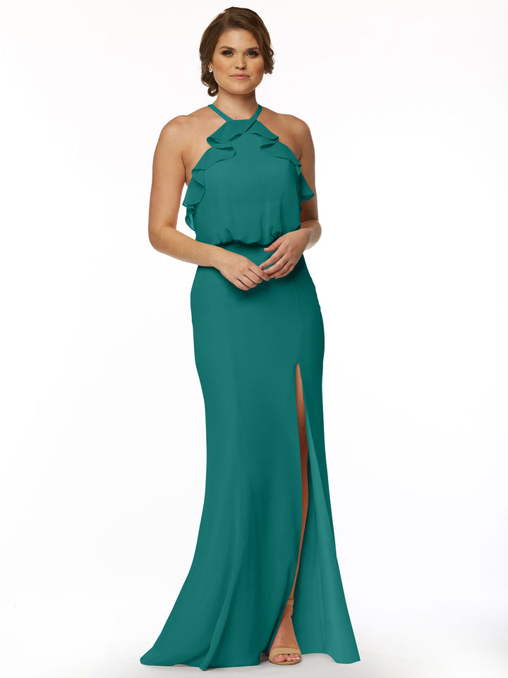 A woman models Avery Austin’s 80147, a fitted chiffon dress with ruffled bodice and front slit, standing against a white background. She has short hair and wears open-toed heels.